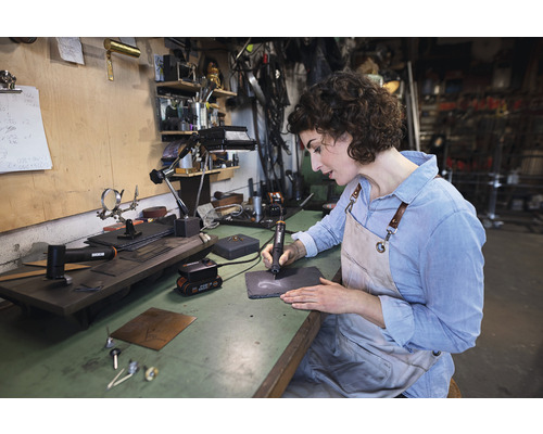 Žena gravíruje bridlicovú dosku gravírovacím nástrojom na pracovnom stole