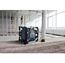 Staveniskové rádio Bosch na stavenisku so stavebnými robotníkmi a stavebnými materiálmi