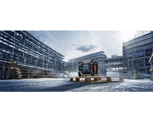 Stavebná scéna so stavebným rádiom na palete pred hrubou stavbou