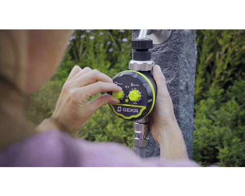 Osoba nastavuje ovládač zavlažovania GEKA, ktorý je pripevnený k vodovodnému kohútiku.