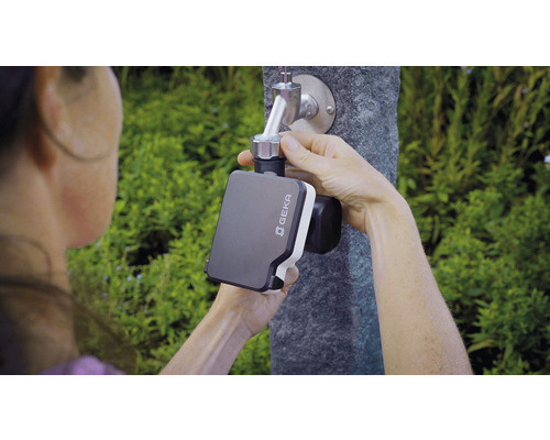 Osoba upevňuje zavlažovací ovládač Geka na záhradný kohútik.