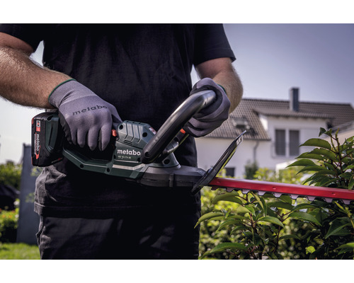 Osoba s akumulátorovými nožnicami na živý plot Metabo pri strihaní živého plota