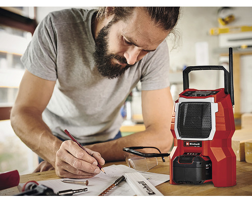 Muž si robí poznámky vedľa červeného staveniskového rádia značky Einhell.