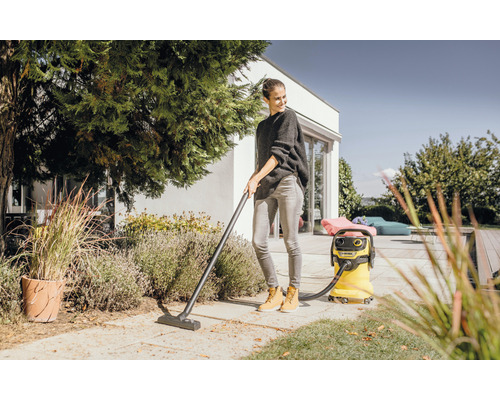 Žena upratuje terasu viacúčelovým vysávačom.