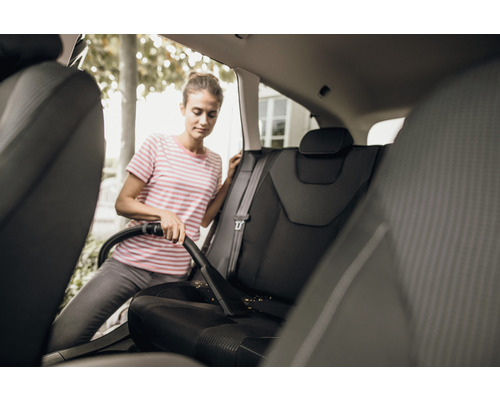 Žena vysáva autosedačky vysávačom.