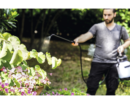 Muž používa záhradný postrekovač na ošetrovanie rastlín
