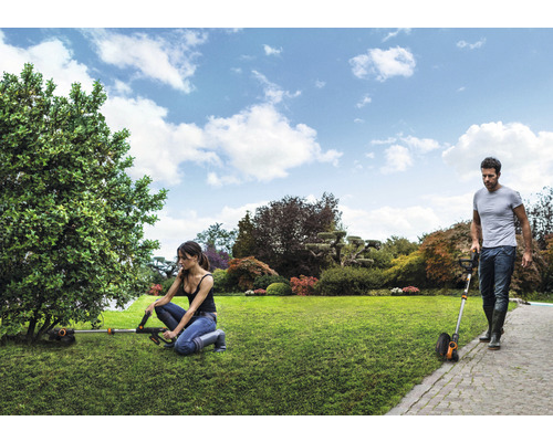 Záhradná scéna so kosačkami na trávu pracujúcimi v záhrade.