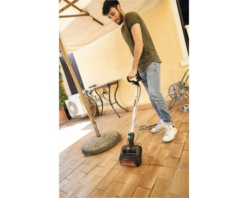 Muž používa elektrický čistič terás na dláždenej terase.