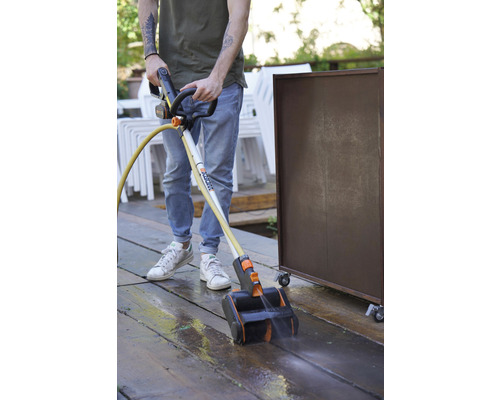 Osoba čistí drevenú terasu čističom terás Worx.