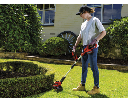 Žena používa akumulátorový vyžínač v záhrade.