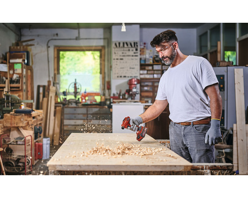 Muž hobľuje drevo akumulátorovým hoblíkom v dielni.