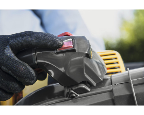 Ruka s ochrannou rukavicou ovláda spínač fúkača lístia