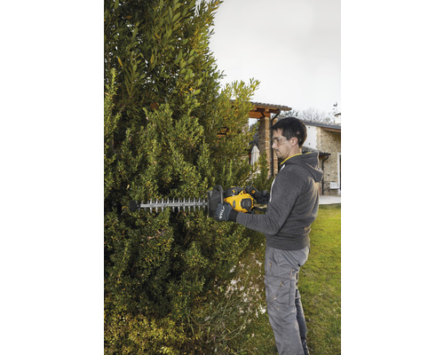 Muž strihá živý plot pomocou nožníc na živý plot v záhrade.