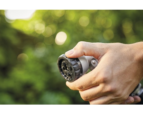 Ruka drží striekaciu hlavicu záhradnej hadice