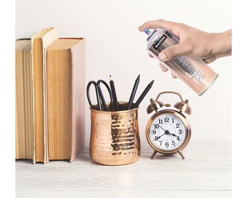 Scéna s knihami, držiak na perá s perami, budík a plechovka metalického spreja