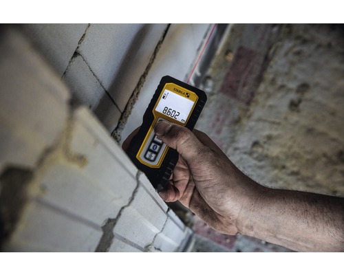 Ruka s laserovým diaľkomerom Stabila meria stenu