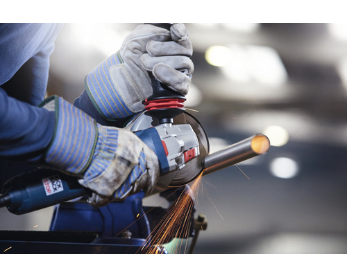 Osoba brúsi kovovú rúrku uhlovou brúskou v zveráku