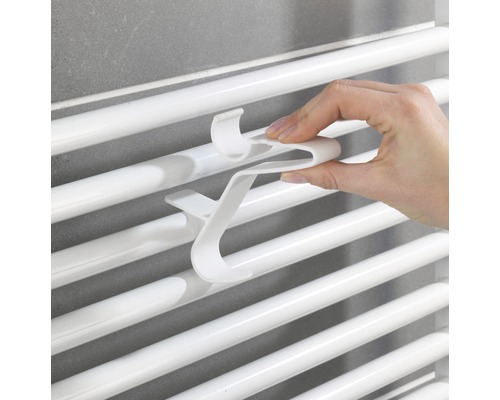 Ruka pripevňuje háčik na uteráky k radiátoru