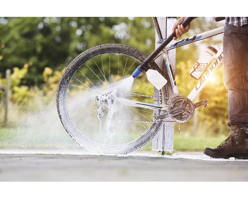 Osoba čistí bicykel vysokotlakovým čističom.