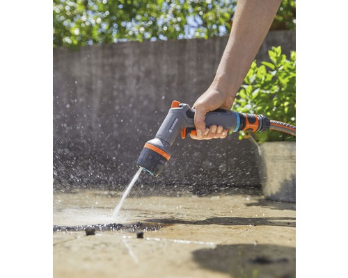 Osoba používa viacúčelovú sprchu Gardena na zavlažovanie povrchu.