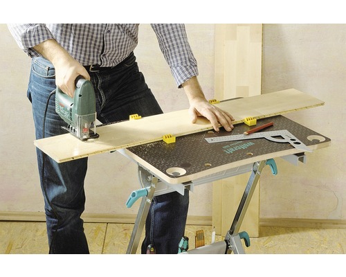 Osoba reže drevenú dosku priamočiarou pílou na pracovnom stole.