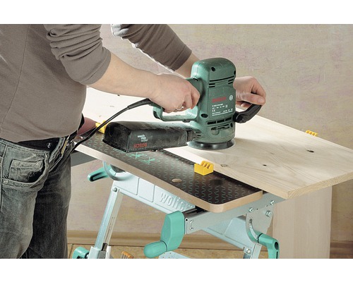 Osoba používa excentrickú brúsku značky Bosch na pracovnom stole Wolfcraft na spracovanie dreva.