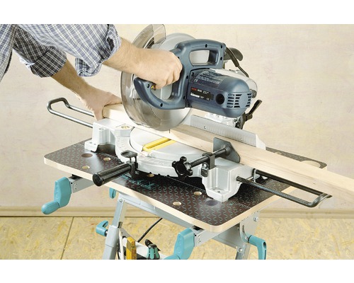 Osoba reže drevenú dosku pokosovou pílou na pracovnom stole.