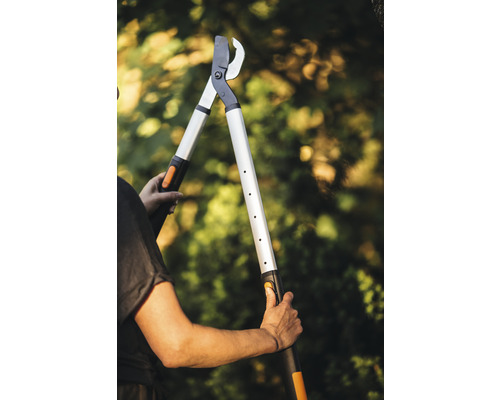 Osoba drží nožnice na konáre s dlhou rukoväťou