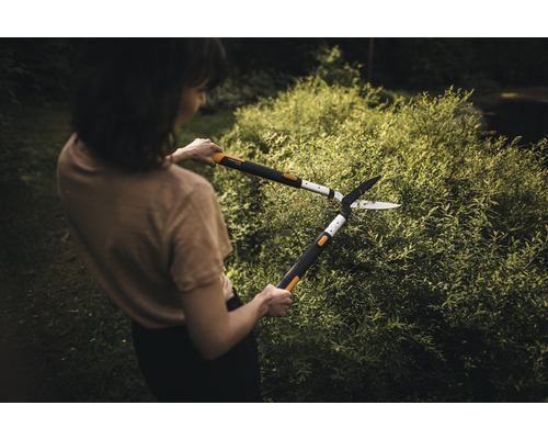 Žena strihá živý plot nožnicami na živý plot