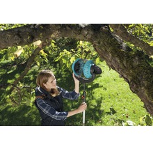 Žena používa zberač ovocia v záhrade pod stromom.