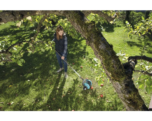 Žena používa zberač ovocia v záhrade pod stromom.