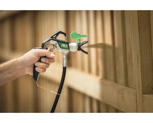 Striekacia pištoľ na farbu používaná pred dreveným plotom