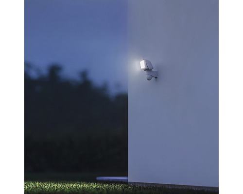 Vonkajšie nástenné svietidlo s pohybovým senzorom osvetľuje stenu domu v noci.