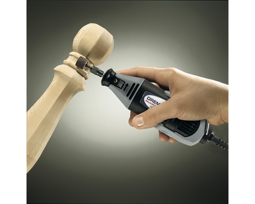 Multifunkčný nástroj Dremel opracováva kus dreva