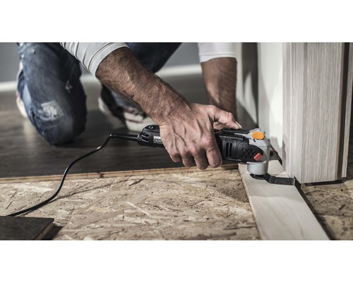 Muž používa multifunkčný nástroj na rezanie kusu dreva