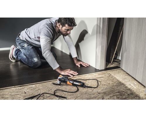 Muž pracuje s multifunkčným nástrojom Worx na podlahe.