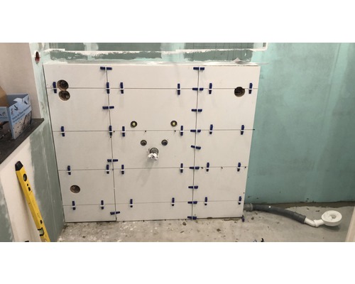 Obkladové dlaždice v kúpeľni s dlaždicovým príslušenstvom a vodováhou.