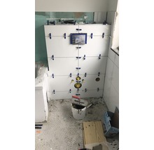 Renovácia kúpeľne s bielymi obkladmi na stene a náradím