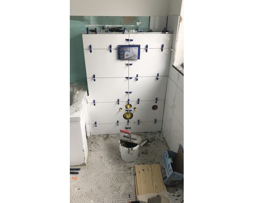 Renovácia kúpeľne s bielymi obkladmi na stene a náradím