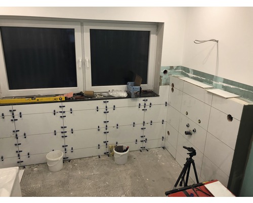 Kúpeľňa vo výstavbe s obkladmi na stenách, okno a náradie