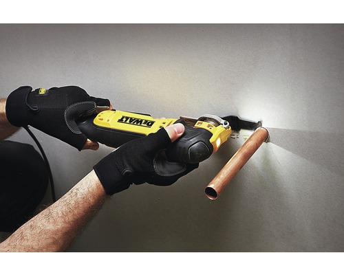 Osoba používa oscilačnú pílu Dewalt na rezanie medenej rúrky.