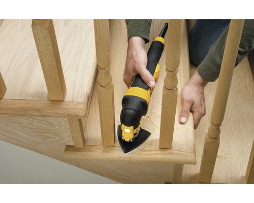 Osoba používa multifunkčný nástroj na brúsenie dreveného schodiskového zábradlia.