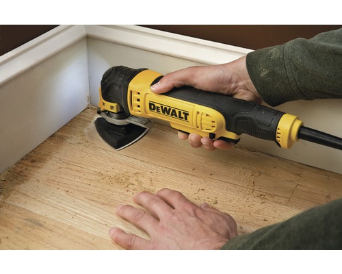 Scéna zobrazuje osobu pracujúcu s drevom pomocou multifunkčného nástroja značky Dewalt.