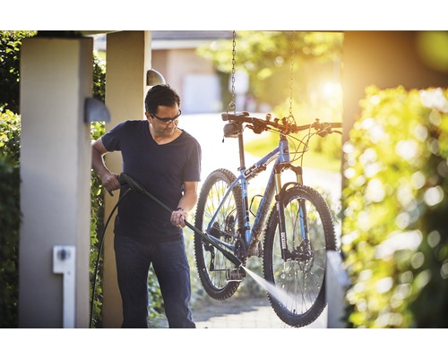 Muž čistí bicykel pomocou tlakovej umývačky