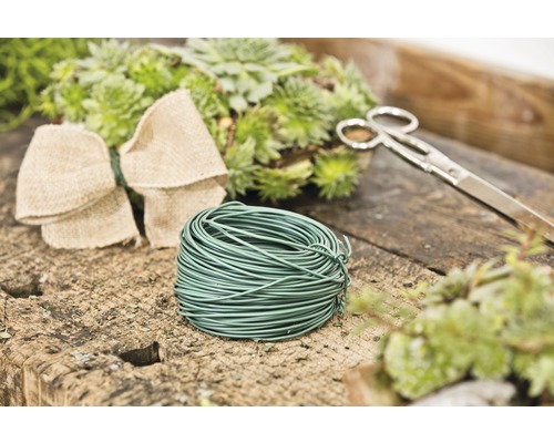 Kvetinársky drôt, nožnice, mašľa a rastliny na stole