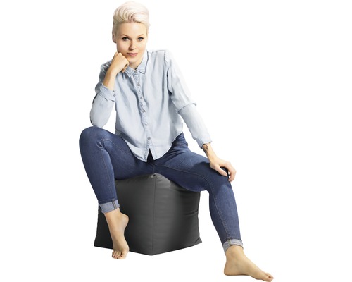 Žena sedí na sivej sedacej kocke