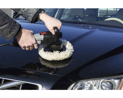 Muž leští kapotu auta leštičkou.