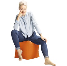 Žena sedí na sedacej kocke v interiéri