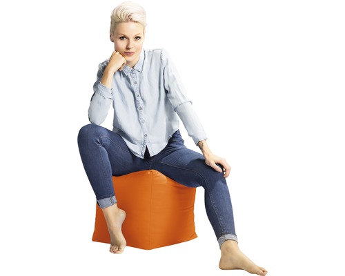 Žena sedí na sedacej kocke v interiéri