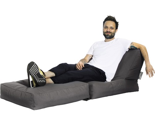 Muž odpočíva na sivom sedacom vaku s podnožkou